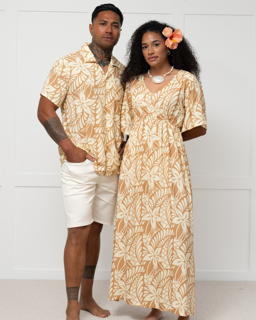 Man and woman wearing matching floral outfits against a white background