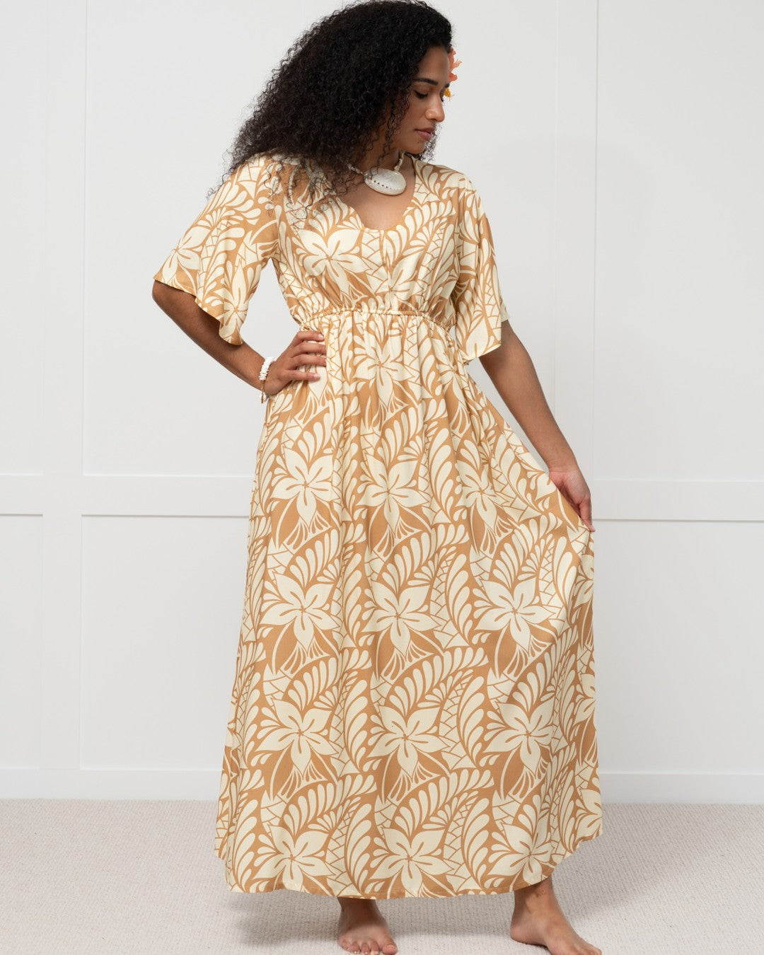Woman wearing a long, patterned island dress against a white background
