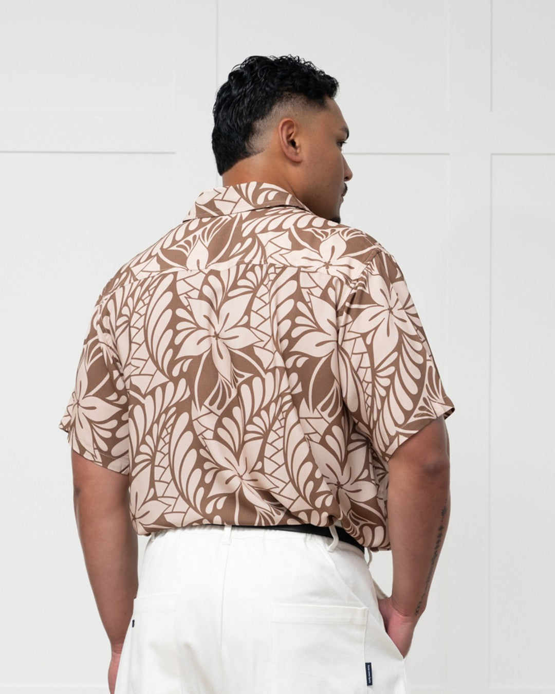 Man wearing a brown floral-patterned island shirt against a white background