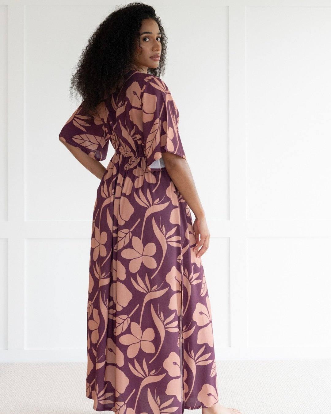 Woman wearing a purple floral island dress with a white background