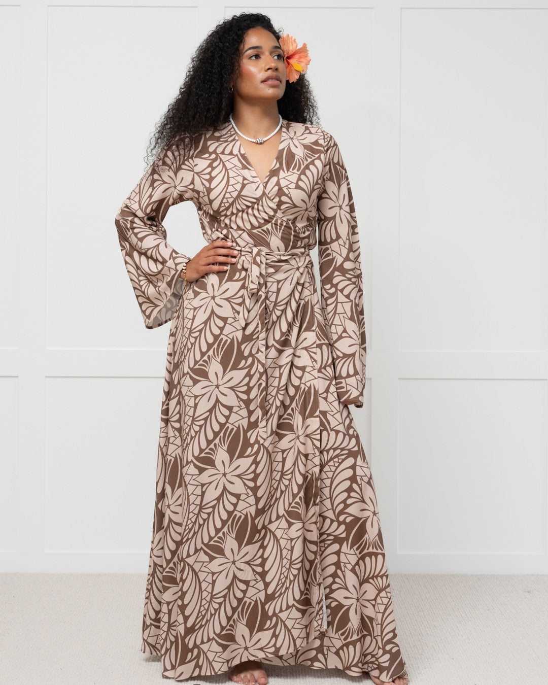 Couple in matching outfits standing in water at sunset on a beach.