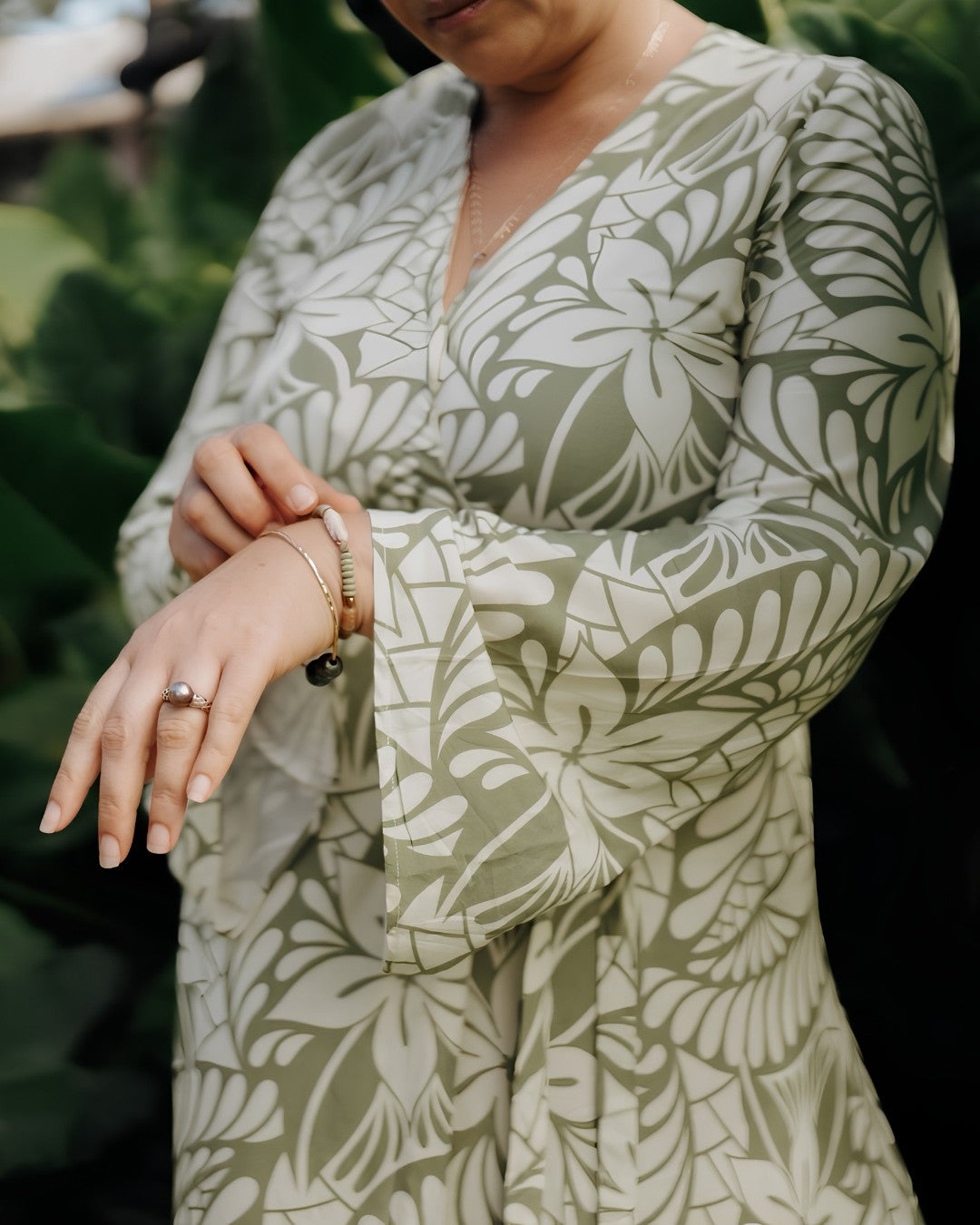 Person wearing a green and white patterned dress with a blurred natural background